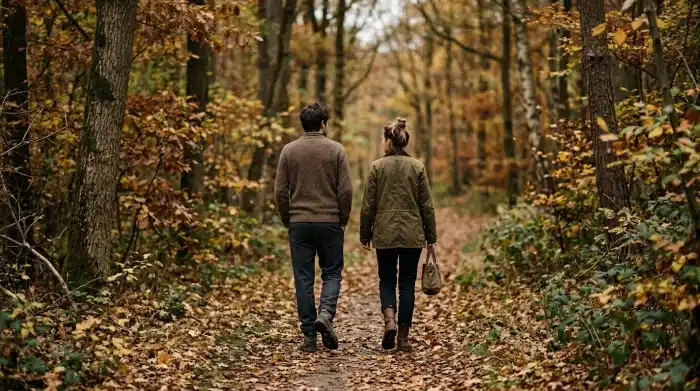 beziehung retten durch abstand: Paar mit etwas Raum zwischen sich, auf einem herbstlichen Waldweg mit fallenden Blättern